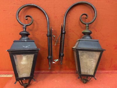 deux lanternes noires accrochées l'une à côté de l'autre sur un mur rouge