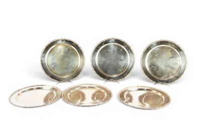 trois assiettes en argent et un plateau en argent posés sur une surface blanche