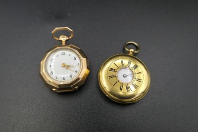 deux montres de poche dorées sur un fond noir