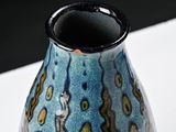 a blue vase sitting on a white table with a black base