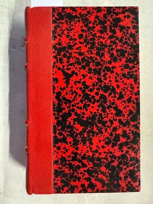 un livre rouge et noir posé sur une table blanche
