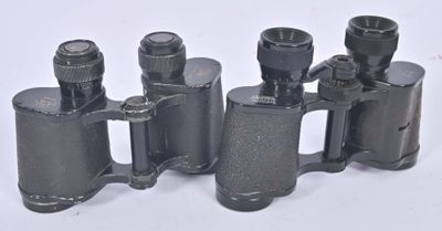 three black binoculars are lined up on a white surface