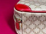 a white and red purse sitting on a pink surface