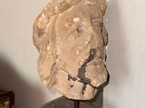 a stone head on a wooden stand in a room
