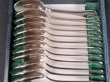 six silver spoons in a case with a green lining