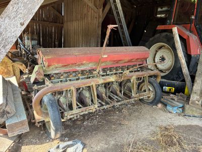 un tracteur garé dans une grange, avec une charrue attelée derrière