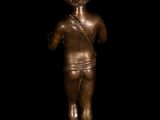 a bronze statue of a young boy holding a tennis racquet