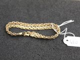 a close up of a gold chain bracelet with a tag on it