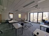 une pièce équipée de tables et de chaises, d'où l'on a une vue sur la ville