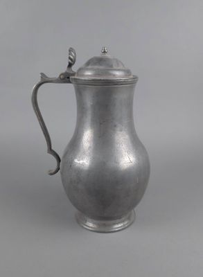 une cafetière ancienne en argent avec une anse, sur fond gris