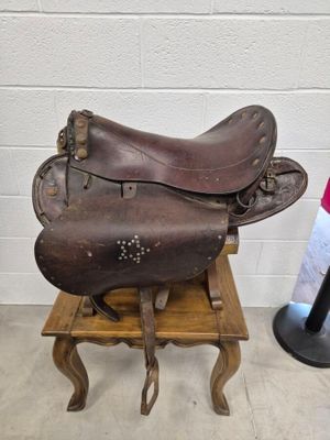 une selle de cheval posée sur un tabouret en bois