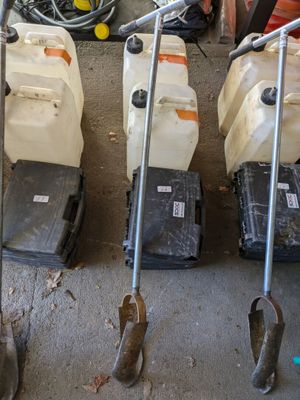 Trois tondeuses à gazon sont alignées les unes à côté des autres dans un garage.