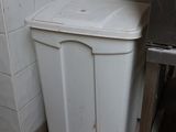a trash can in the corner of a kitchen next to a stove