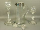 a glass pitcher and two glass candlesticks on a table