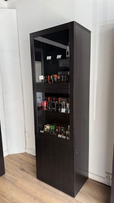a tall black cabinet with a lot of bottles in it