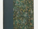 an old book with a green cover sitting on a white surface