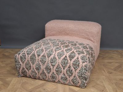 an upholstered footstof with a pink and grey geometric design