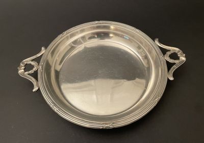 un plateau ancien en argent avec des poignées, posé sur une table noire