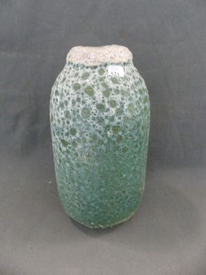 un vase vert posé sur une table sur fond noir