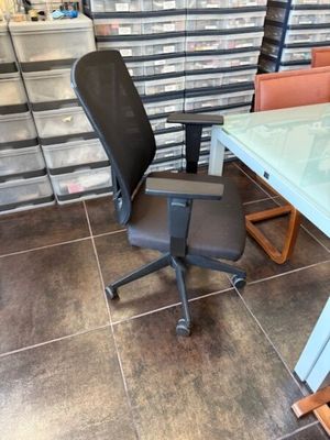 une chaise de bureau noire placée devant une table en verre