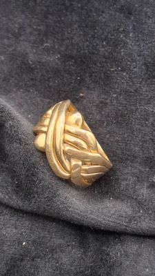 un gros plan d'une bague en or posée sur un tissu noir