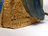 a gold and blue statue of a woman on a rock