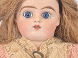 a close up of a doll with blue eyes and a pink dress
