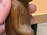 a person holding a wooden bear figurine on a desk