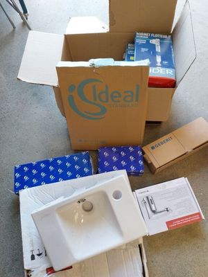 une pile de cartons et un évier posé à même le sol