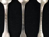 three silver spoons are lined up on a black surface