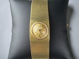 an image of a gold wrist watch on a black pillow