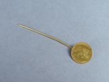 a close up of a gold coin with a long stick sticking out of it