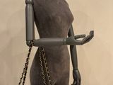 mannequin holding a black chanel bag with a gold chain strap