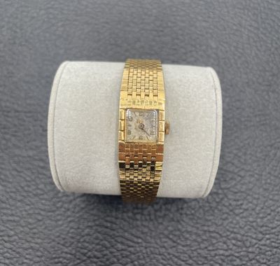 un gros plan d'une montre-bracelet en or posée sur une bague blanche