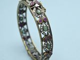 a close up of a gold ring with pink and green stones