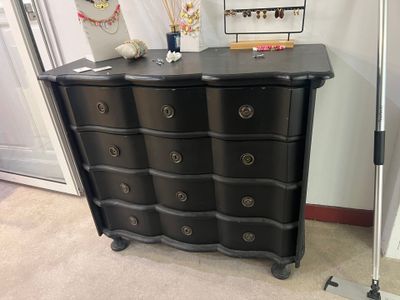 une commode noire dans une pièce où un miroir est accroché au mur