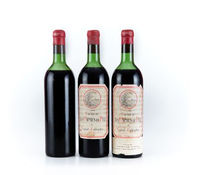 trois bouteilles de vin rouge posées l'une à côté de l'autre sur une surface blanche