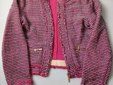 a close up of a pink sweater and jacket hanging on a wall