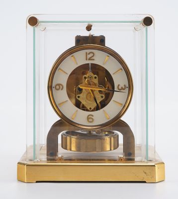 une horloge posée sur une table, dans une vitrine en verre