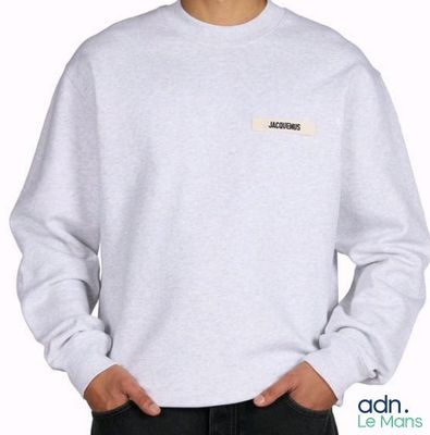 un jeune homme portant un sweat-shirt gris avec un écusson sur la poitrine