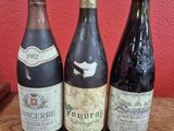 three bottles of wine sit on a table in front of a red wall