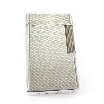 un briquet argenté posé sur une surface blanche
