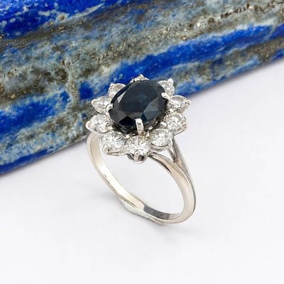 a close up of a ring with a black diamond surrounded by white diamonds