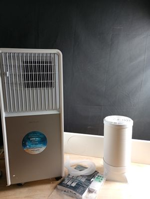 a small air conditioner sitting on the floor next to a trash can