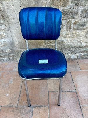 une chaise bleue, sur laquelle est posée une étiquette, posée sur un sol carrelé