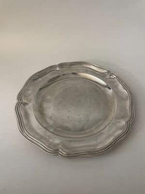 assiette en argent plaqué avec un bord festonné sur un fond blanc