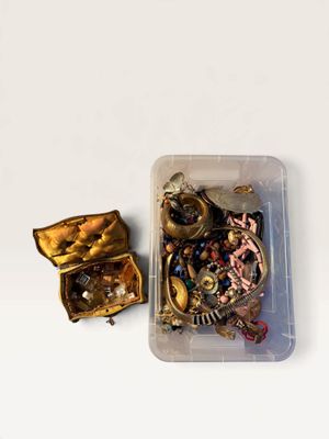 a small container filled with assorted jewelry on a white surface