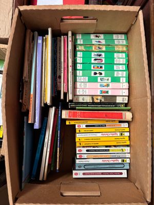 une boîte en carton remplie de livres posée sur une étagère