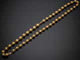 a gold bead necklace on a black background