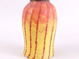 un vase jaune et rouge posé sur une surface blanche